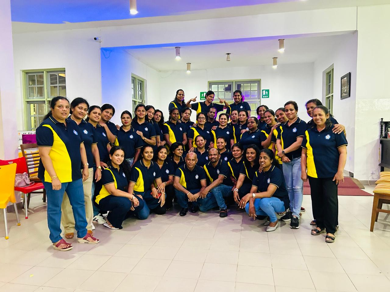 Large staff group in custom navy polos with yellow side panels and embroidered crest